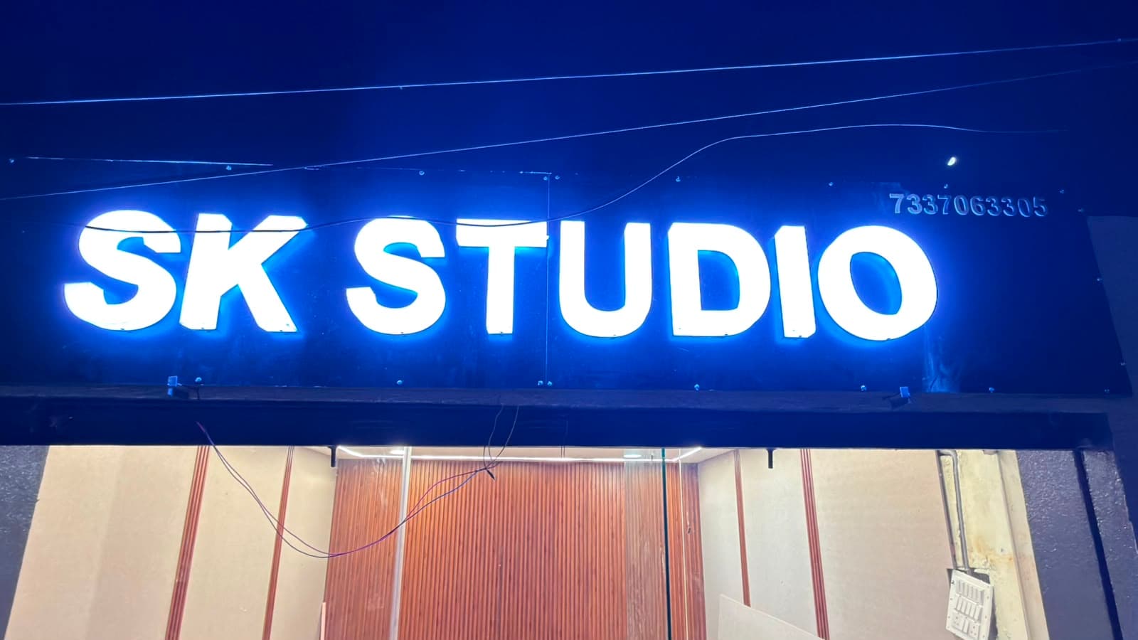 Illuminated SK Studio entrance sign with the studio interior visible below